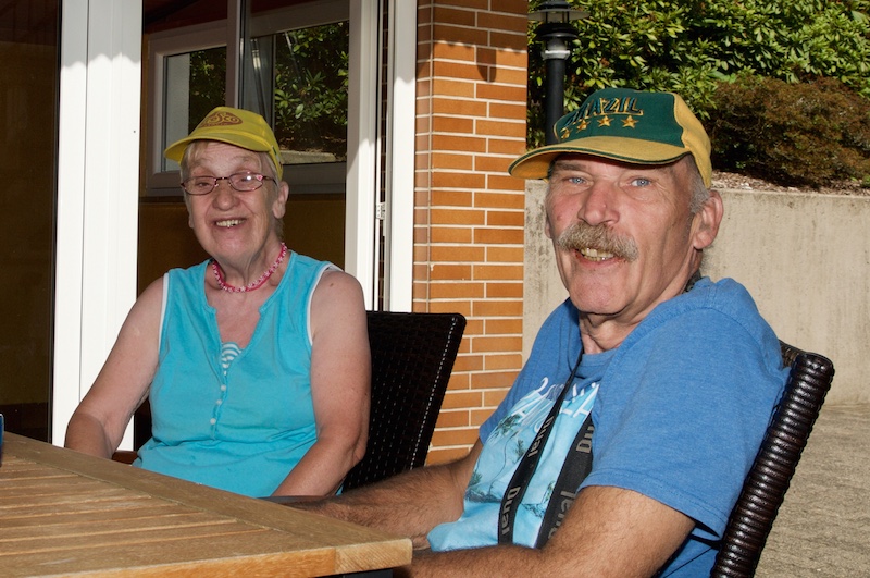 Bewohnerin und Bewohner mit Sonnenhüten lächeln in die Kamera